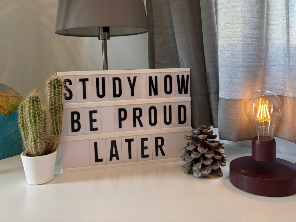 Desktop scene with motivational message - study now be proud later
